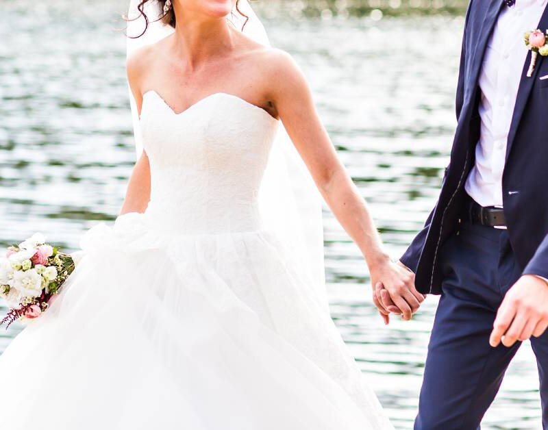 Newly married couple walking with beach in the back.